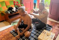Bripka Untung sedang melakukan pengobatan gratis bekam  kepada salah seorang warga.