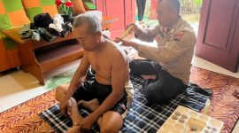 Bripka Untung sedang melakukan pengobatan gratis bekam  kepada salah seorang warga.