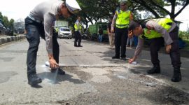 Personel Polres Demak melakukan pengecatan lubang jalan di Jalan Pantura KM 31 + 200 Semarang-Kudus, Desa Bolo, Kecamatan Demak, Kabupaten Demak, Selasa (18/2).