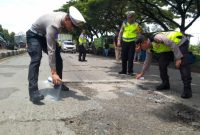 Personel Polres Demak melakukan pengecatan lubang jalan di Jalan Pantura KM 31 + 200 Semarang-Kudus, Desa Bolo, Kecamatan Demak, Kabupaten Demak, Selasa (18/2).