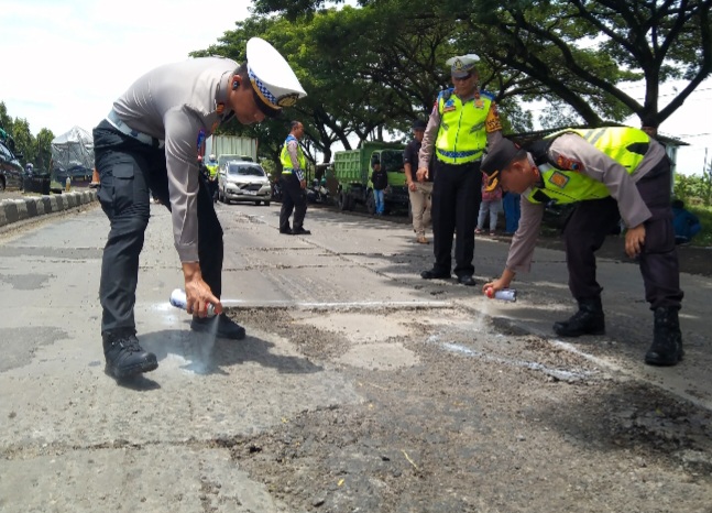 Personel Polres Demak melakukan pengecatan lubang jalan di Jalan Pantura KM 31 + 200 Semarang-Kudus, Desa Bolo, Kecamatan Demak, Kabupaten Demak, Selasa (18/2).