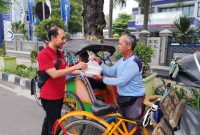 Petugas tim bakti sosial kolaborasi dari Ikatan Apoteker Indonesia Cabang Rembang, Dinas Kesehatan Kabupaten dan dari Gereja Mahanaim sedang menyerahkan takjil kepada seorang pengemudi becak di jalan Kartini Rembang, Jum'at (7/3/2025).