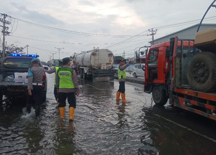 Para personil Polsek Sayung sedang membagikan takjil kepada pengguna jalan Pantura Semarang – Demak, Sabtu (8/3/2025).
