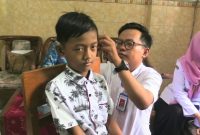 Seorang petugas sedang memasang alat bantu dengar bantuan pemerintah pada penyandang disabilitas, Rabu (12/3).