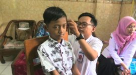 Seorang petugas sedang memasang alat bantu dengar bantuan pemerintah pada penyandang disabilitas, Rabu (12/3).