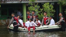 Anggota Polres Demak sedang membantu siswa di Desa Sayung dan Lengkong dengan perahu ke sekolah karena terdampak banjir.
