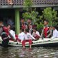 Anggota Polres Demak sedang membantu siswa di Desa Sayung dan Lengkong dengan perahu ke sekolah karena terdampak banjir.
