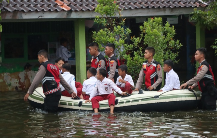 Anggota Polres Demak sedang membantu siswa di Desa Sayung dan Lengkong dengan perahu ke sekolah karena terdampak banjir.
