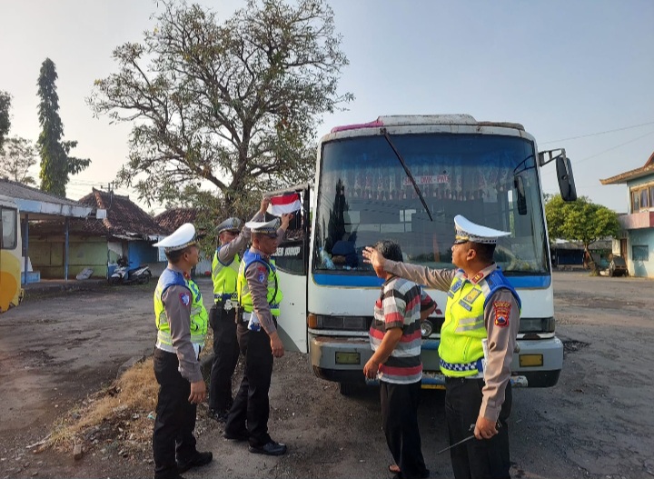 Anggota Satuan Lalu Lintas (Satlantas) Polres Demak sedang memasang bendera di salah satu bus angkutan umum di Terminal Bintoro Demak dan pangkalan ojek, Selasa (5/8/25).