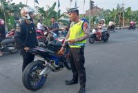 Petugas Satlantas Polres Demak sedang menghentikan pengendara sepeda motor yang menggunakan knalpot tidak sesuai spesifikasi teknis, dalam Operasi Zebra Candi 2025.