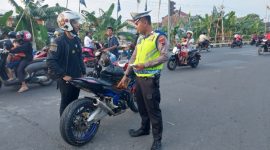 Petugas Satlantas Polres Demak sedang menghentikan pengendara sepeda motor yang menggunakan knalpot tidak sesuai spesifikasi teknis, dalam Operasi Zebra Candi 2025.