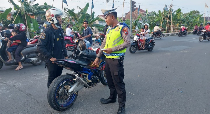 Petugas Satlantas Polres Demak sedang menghentikan pengendara sepeda motor yang menggunakan knalpot tidak sesuai spesifikasi teknis, dalam Operasi Zebra Candi 2025.