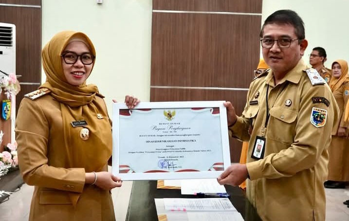 Bupati Demak, Eisti’anah menyerahkan penghargaan kepada Plt. Kadinkominfo, Umar Surya Suksmana di Gedung Gradhika Bina Praja, Senin (26/01/26).