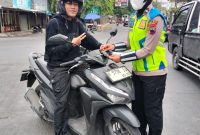 Anggota Satlantas Polres Demak menyosialisasikan Operasi Patuh Candi 2026 dengan membagikan pamflet kepada pengguna kendaraan,  Selasa (28/10/2026).