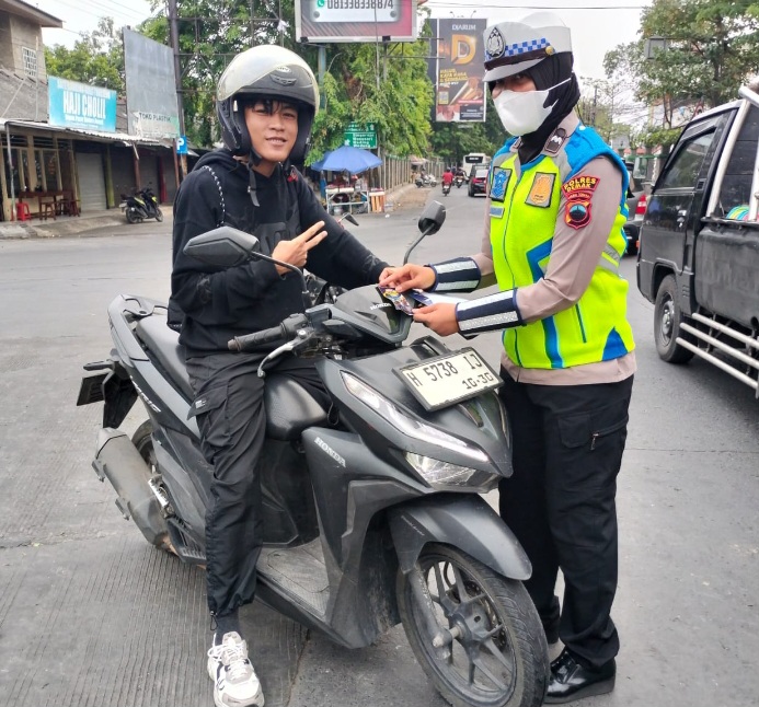 Anggota Satlantas Polres Demak menyosialisasikan Operasi Patuh Candi 2026 dengan membagikan pamflet kepada pengguna kendaraan,  Selasa (28/10/2026).