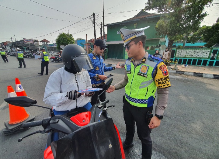 Anggota Satlantas Polres Demak mensosialisasikan tertib berlalu lintas dan pembayaran pajak kendaraan bermotor di kawasan Alun-alun Demak, Jum'at (30/10/2026).